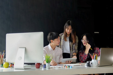 Fototapeta premium Designers Brainstorming concept : Young creative designer team working with new startup project in modern office. Contemporary notebook on wood table.