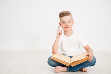 Happy boy with big book showing finger up. Space for text