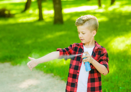 Boy spraying insect repellents on skin