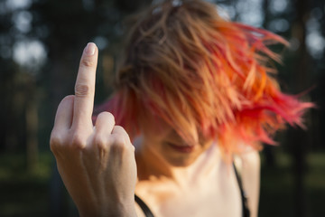 Red-haired girl showing middle finger gesture. Redhead woman showing a fuck you off sign