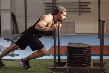 Muscular and strong young man pushing the exercise equipment at the gym