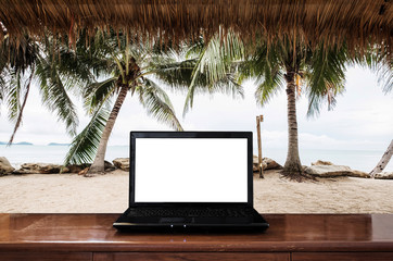 Computer laptop on wooden table, at the beach in ummer. Clipping path empty white screen 