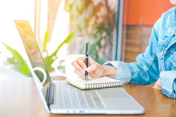 woman's hand works in a notebook and is writing on a pen notepad in the office.