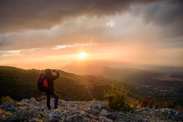 Fototapeta premium Amazing sunset on a mountain top - man with alpine equipment enjoying the breathtaking view under the stormy sky