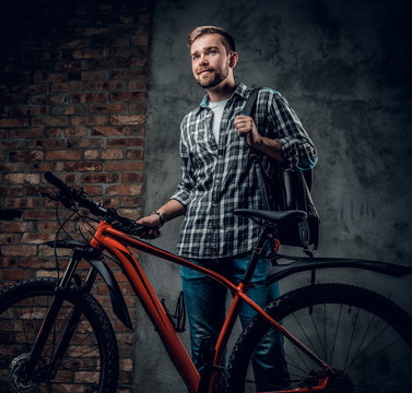 A mant holds red mountain bicycle.