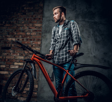 A mant holds red mountain bicycle.