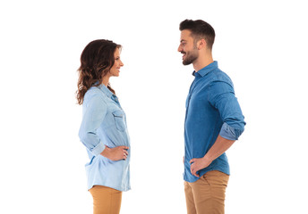 casual couple standing with hands on waist facing each other