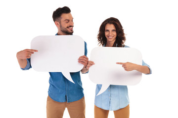 casual couple holding speech bubbles pointing to each other