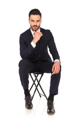 young pensive business man is sitting on a chair