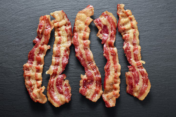 Cooked bacon rashers on the background of a slate board