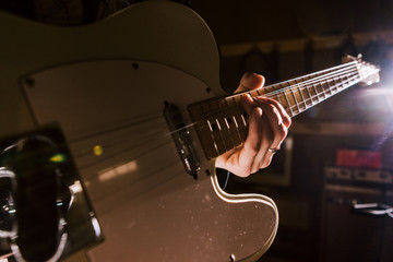 Fototapeta premium Electric guitar in guitarist hands closeup. Music band rehearsal before concert, recording studio