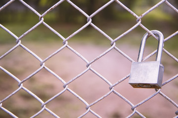 Old master key locked on metal fence with copy space. Vintage tone.