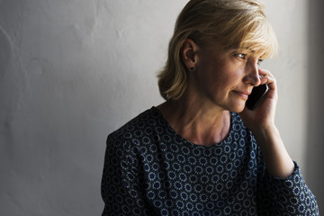 Closeup of caucasian woman calling mobile phone with thoughtful face expression