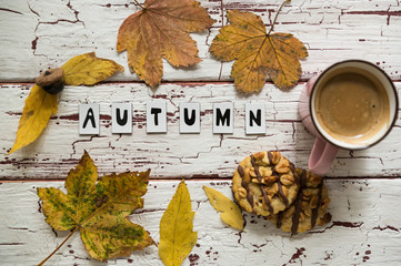 Close up of yellow leaves and corns on rustic white wooden background. Cup of coffee americano with...
