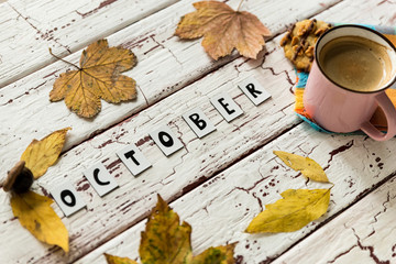 Close up of yellow leaves and corns on rustic white wooden background. Cup of coffee americano with...