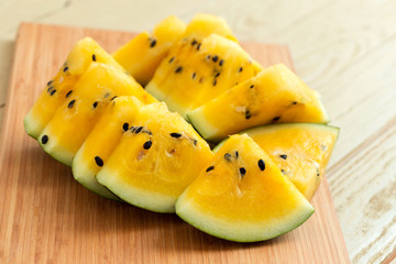 Yellow watermelon sliced on wooden background