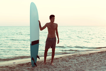 Fototapeta na wymiar Handsome surfer holding his surfboard