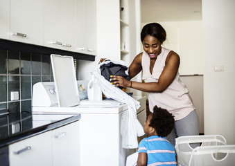 African descent kid helping mom doing the laundry