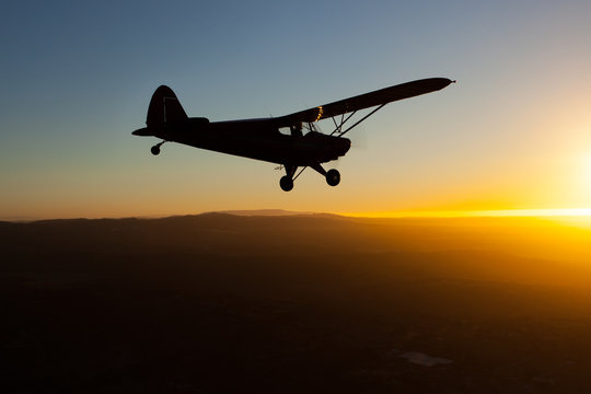 Romantic airborne evening: beautiful silhouette of a plane flying towards the setting sun