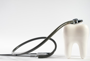 White healthy tooth and stethoscope in dentist's office