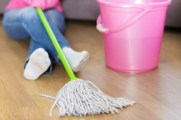 tired woman in protective gloves is sitting near bucket.