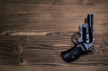 Obraz premium Gun revolver on wooden table background. Handgun on table surface.