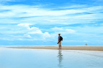 Young traveler man with backpack standing at seaside and looking to the ocean