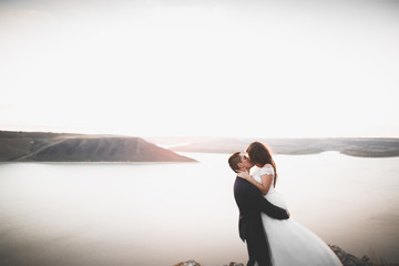 Elegant stylish happy wedding couple, bride, gorgeous groom on the background of sea and sky