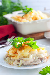 Potato Gratin with onion and pork on a white plate, selective focus