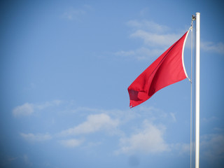 red flag for rough sea over a lifeguard tower long an Italian beach