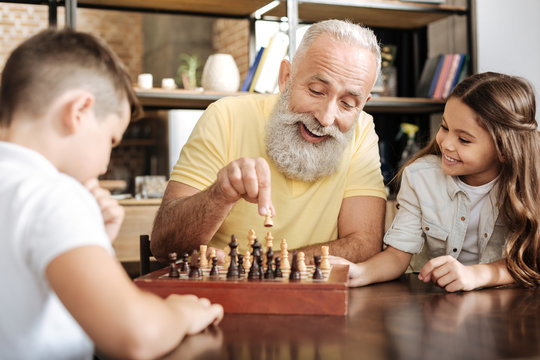 Little girl watching her brother and grandfather play chess