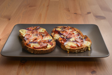 Delicious seasoned savory Italian tomato bruschetta slices on a rustic wooden board garnished with fresh basil leaves.