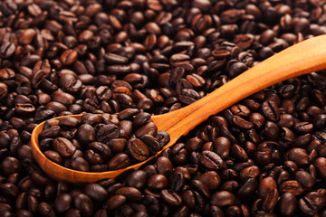 Roasted coffee beans close-up view, background and texture with wooden spoon
