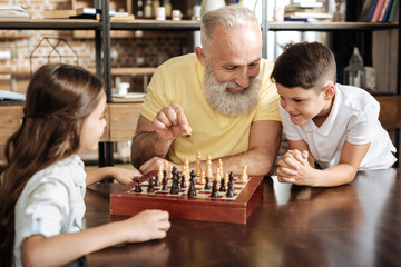 Grandfather showing his grandchildren how to play chess