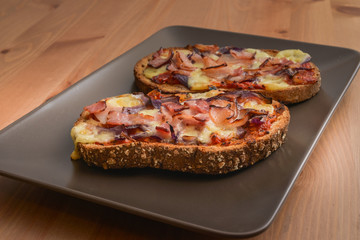 Delicious seasoned savory Italian tomato bruschetta slices on a rustic wooden board garnished with fresh basil leaves.
