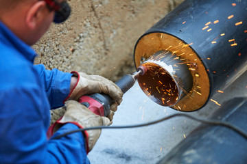 Electric wheel grinding on steel pipe 
Metal worker grinding metal of pipeline