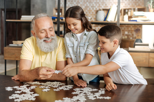 Siblings and their grandfather assembling a jigsaw puzzle