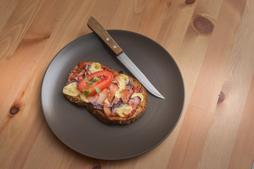 Delicious seasoned savory Italian tomato bruschetta slices on a rustic wooden board garnished with fresh basil leaves.
