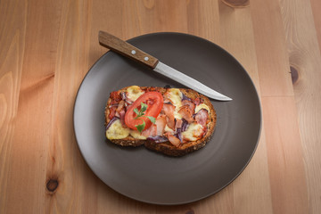 Delicious seasoned savory Italian tomato bruschetta slices on a rustic wooden board garnished with fresh basil leaves.