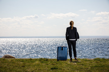 Businesswoman with suitcase standing at seaside