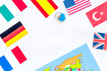 booking trip with map, flags and tourist outfit on white office desk background top view mockup