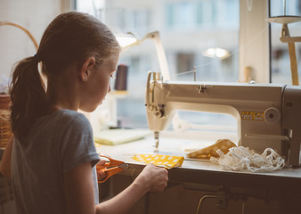 Little girl working on sewing machine at home. - obrazy, fototapety, plakaty