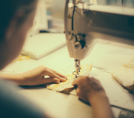 Little girl working on sewing machine at home. Close-up view.