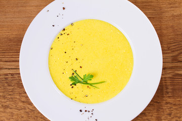 Cream corn soup in bowl on wooden background. View from above, top studio shot