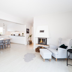 open interior livingroom with lit fire and the kitchen in the background