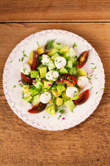 Avocado salad with tomato, cucumber and mozzarella. Cheese and vegetable salad. View from above, top studio shot