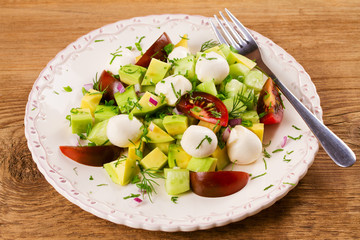 Avocado salad with tomato, cucumber and mozzarella. Cheese and vegetable salad