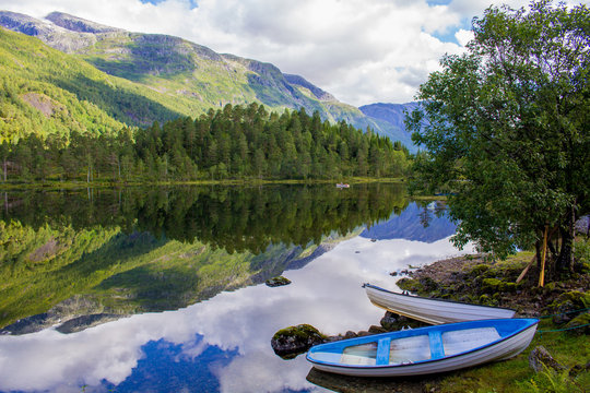Fishing sailing boat on the lake in Norway fjord between the mountains.