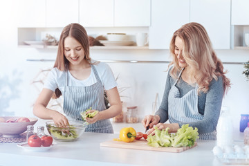 Joyful daughter and mother cooking healthy dinner together