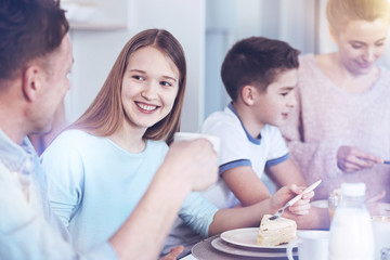 Fototapeta premium Cheerful girl talking to father while eating piece of cake